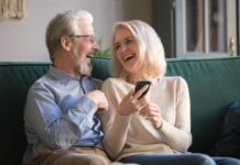 happy retirees family laughing using smartphone home aged husband wife having fun ecommerce shopping watching funny 157924030