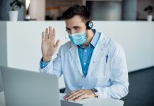 male doctor waving during video call laptop medical clinic 2