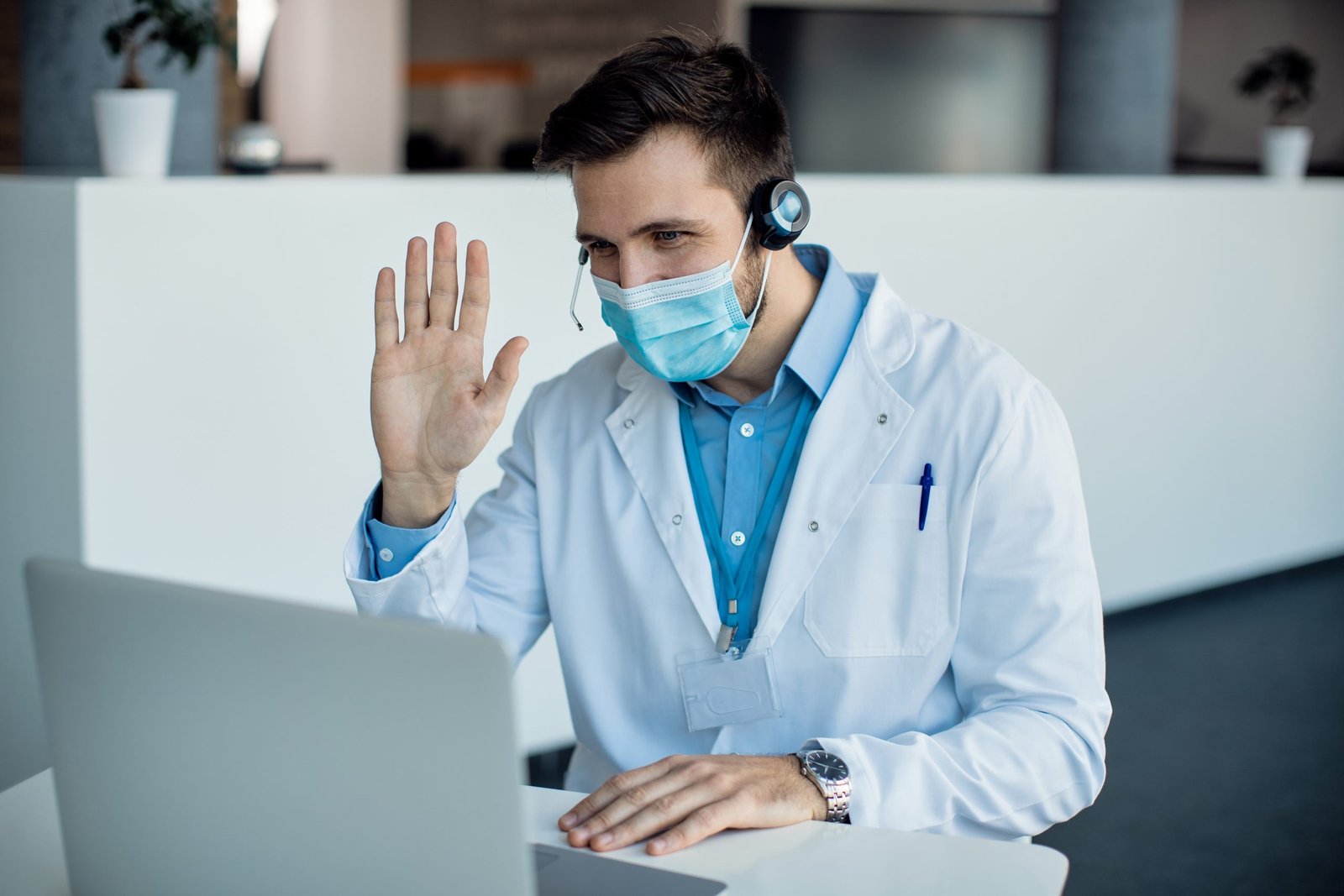 male doctor waving during video call laptop medical clinic 2